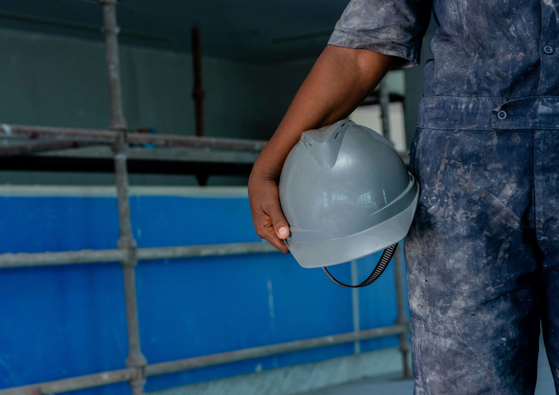 a man in overalls holding a hard hat